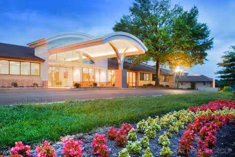 Front view of Delmar Gardens of Chesterfield exterior with curved canopy entrance and landscaping.