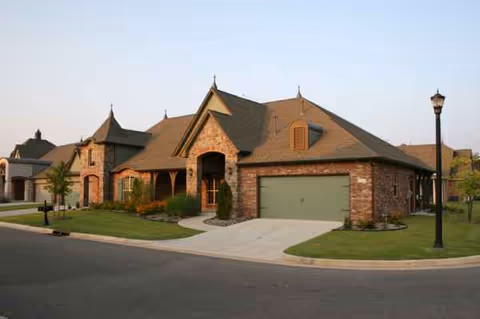 Front view of a brick senior living facility with a two-car garage and manicured lawn.