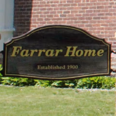 Farrar Home exterior sign on brick building with surrounding greenery.