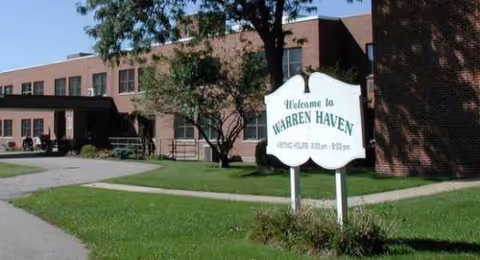 Exterior view of Warren Haven Rehab and Nursing Center with a welcome sign by the lawn.