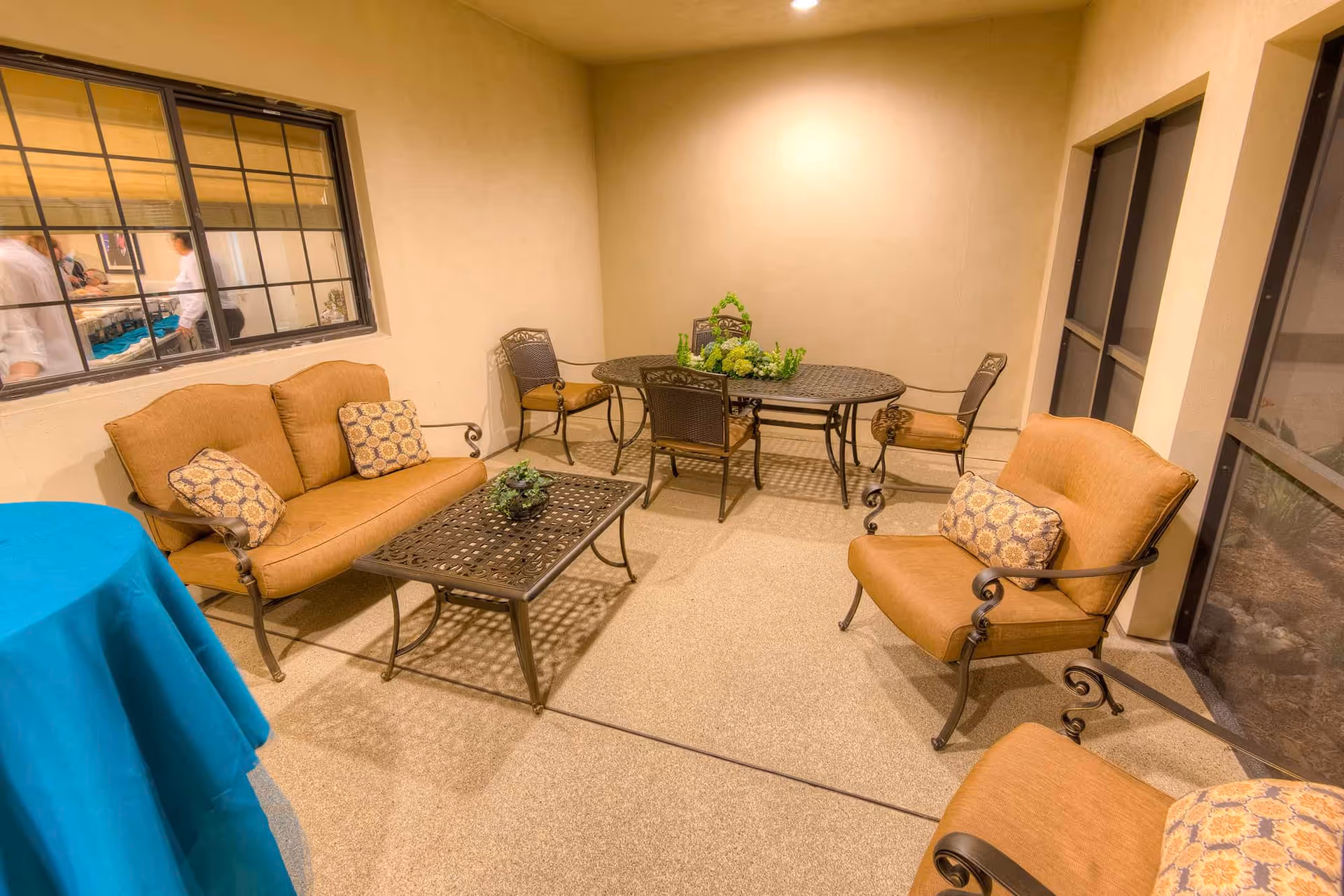 Indoor seating area with cushioned chairs, a loveseat, coffee table and a dining table in a softly lit room.
