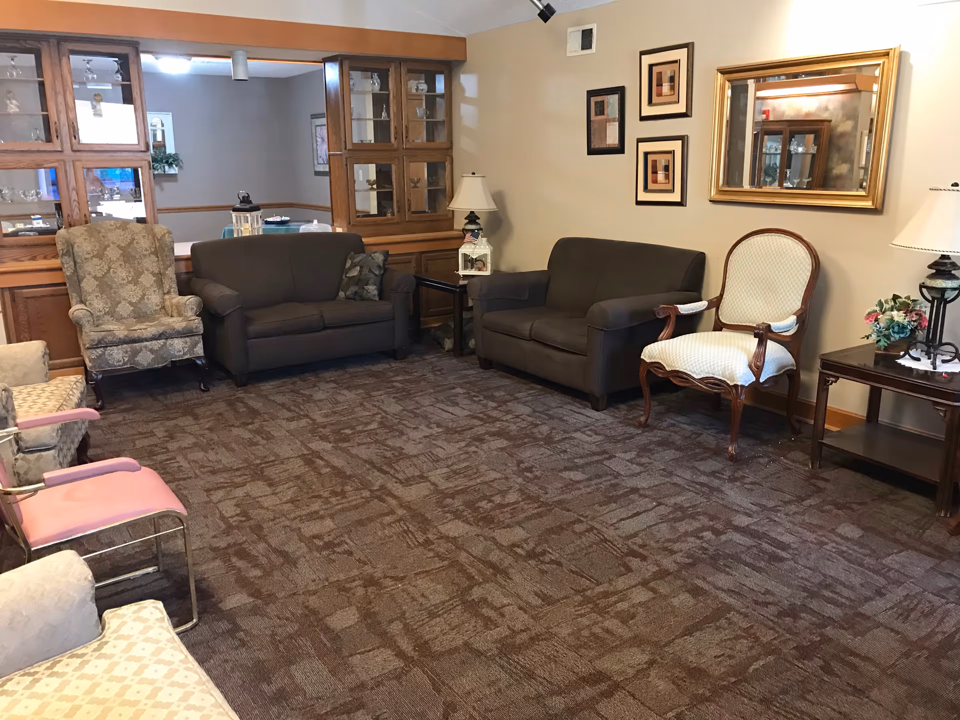 Carpeted sitting room with sofas, armchairs, side tables and framed wall art.