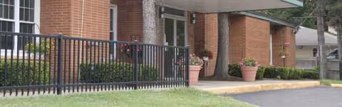 Brick building entrance with railing, planters, and walkway at Eden Rehabilitation and Nursing Center.