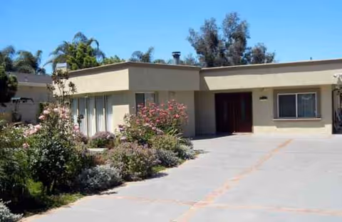 Be Well Senior Living facility front with a driveway and landscaped shrubs.