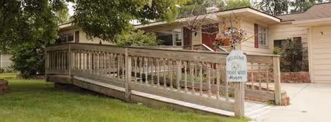 Exterior view of assisted living facility with ramp and hanging flowers.