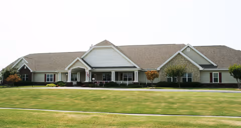 Front exterior of a single-story building with a covered porch, columns, and a large manicured lawn.