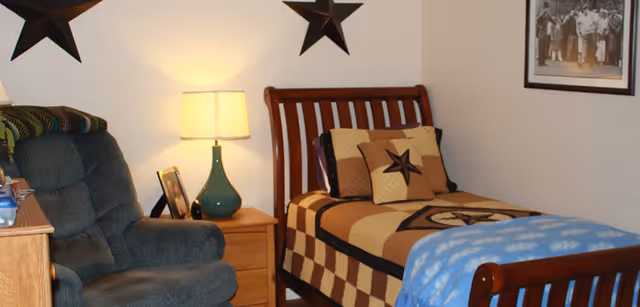 Cozy resident bedroom with a single bed, seating area, lamp, and star decor.
