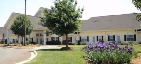 A single-story senior living facility with a curved driveway and landscaped front yard.