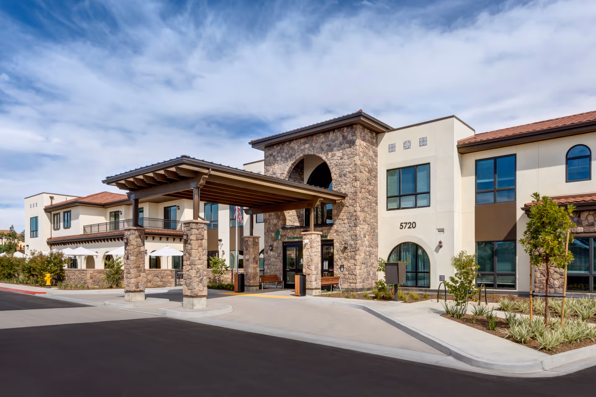 Stone-and-stucco senior living building front with a covered porte-cochère and the address number 5720 visible.