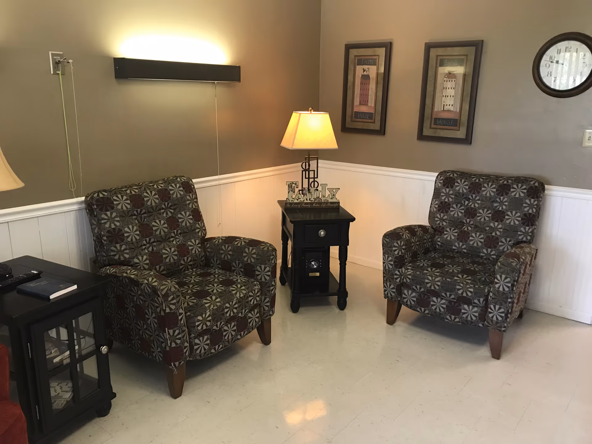 Two patterned armchairs facing each other with a small side table and lamp between them in a cozy sitting area.