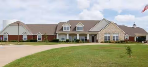 Brookdale Palestine senior living facility exterior with manicured lawn, driveway, and flag.