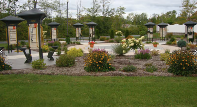 Landscaped outdoor courtyard with a circular walkway, informational kiosks and flowering beds.