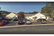 Front exterior view of Warwick Forest senior living campus with parked cars.