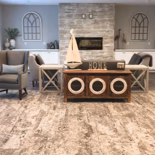 Cozy living room with a stone fireplace flanked by cabinets, armchairs and a coffee table topped with a decorative sailboat and a 'HOME' sign.