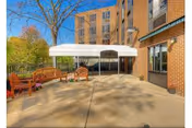 Green Meadows Nursing & Rehabilitation Center exterior with a patio, seating, and a white canopy.