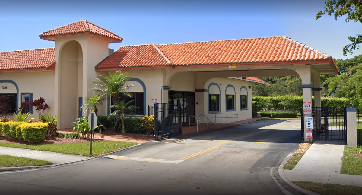 Exterior view of Lake Worth Rehabilitation Center entrance with covered drive and landscaping.
