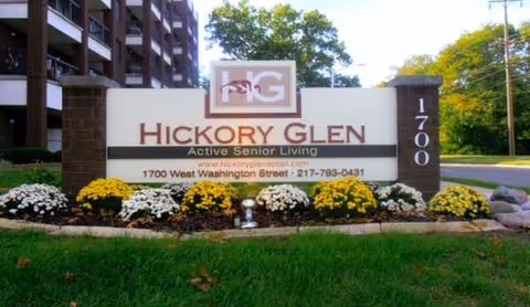 Front sign for Hickory Glen Active Senior Living with landscaped flowers
