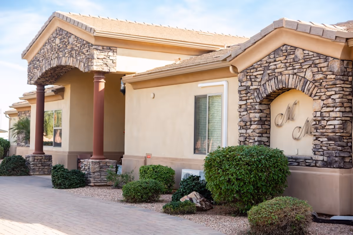 Moonlight Manor exterior featuring stone arches, columned entrance, and landscaped shrubbery.
