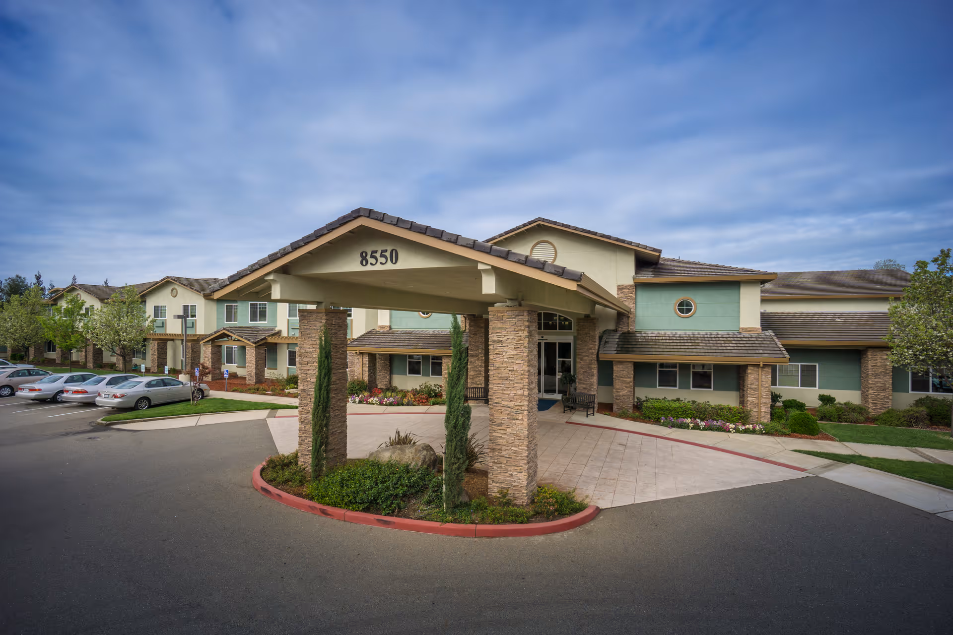 Front entrance of Eskaton Granite Bay with a covered porte-cochere labeled "8550", landscaped driveway and parked cars.