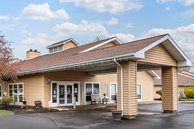 Front entrance of a beige single-story senior living facility with a covered porte-cochere and glass double doors.
