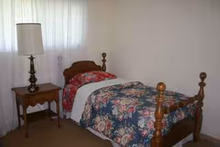 Two twin beds with floral bedspreads, wooden headboards, a nightstand, and a lamp.
