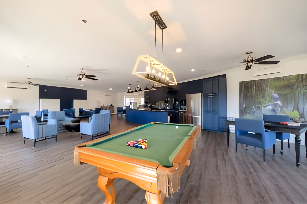 Large communal lounge and game room with a pool table, multiple seating areas, and a bar.