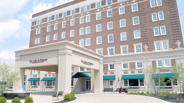 Front entrance and porte-cochere of The Lofts at Roberts, a multi-story brick senior living building.