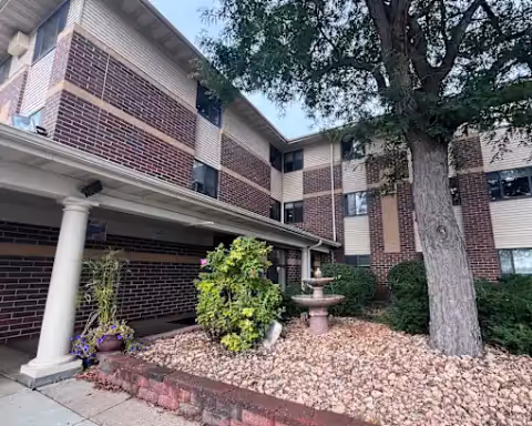 Exterior of Oak Ridge Manor with brick facade, trees, and a small fountain in a landscaped front yard.