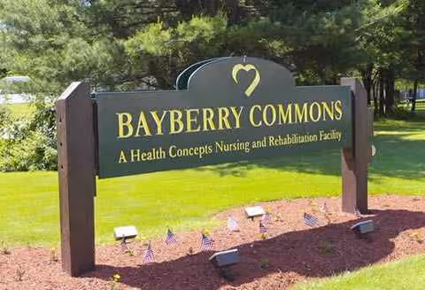 Outdoor view of a Bayberry Commons sign on a green lawn with trees