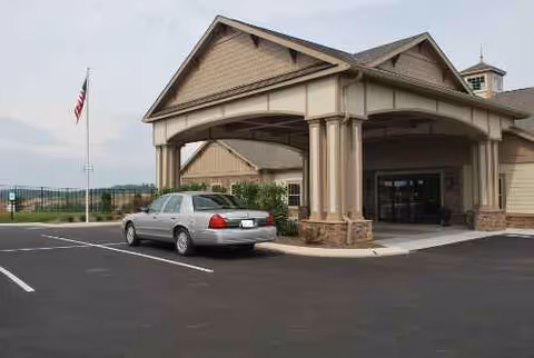 Front exterior of The Lantern at Morning Pointe facility with car and flag in parking area.