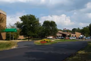 Exterior view of Sanctuary at St Paul's with driveway, trees, and parked cars.