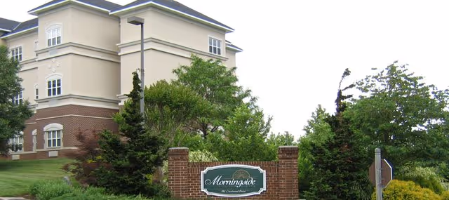 Front exterior of a multi-story beige senior living building with landscaping and a brick sign reading 'Morningside'.