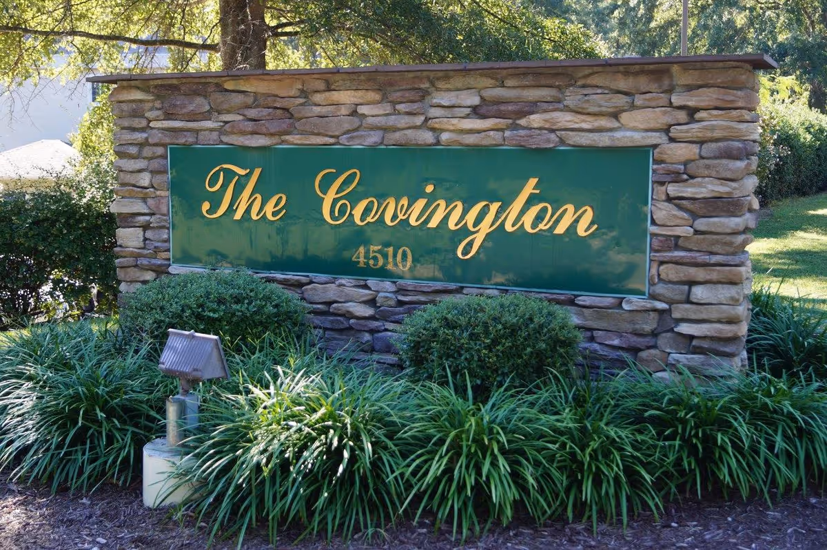 Stone entrance sign reading "The Covington 4510" surrounded by shrubs and landscaping.