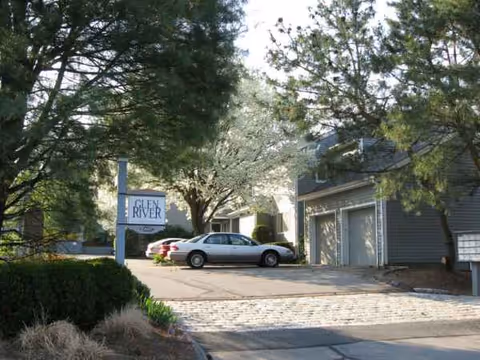 Exterior view of Ogden House senior living facility with parked cars.