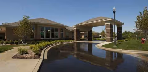 Front entrance of WellBridge of Brighton with a curved driveway and water feature.
