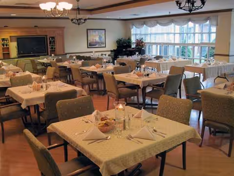 Spacious dining room with neatly set tables, folded napkins, and candles.