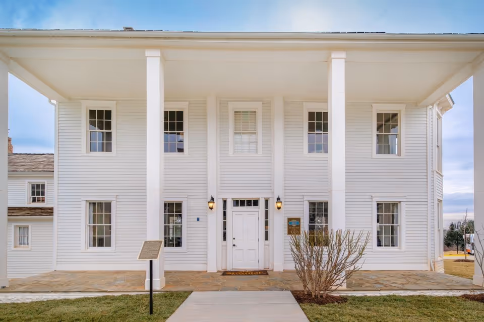 Front exterior of a white two-story colonial-style building with tall columns and a central entrance.