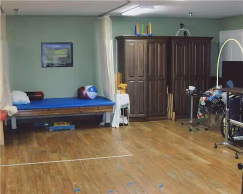 A spacious interior room with a hospital bed, large wooden cabinet, and medical equipment.