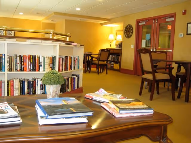 Cozy communal sitting area with bookshelves, tables and chairs and magazines on a coffee table.
