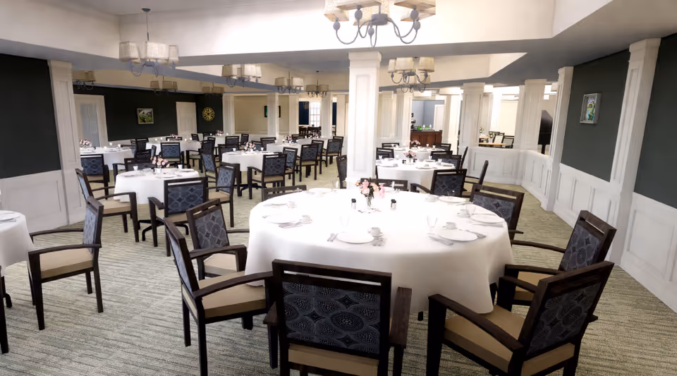 Spacious formal dining room with round tables covered in white tablecloths and dark wooden chairs arranged for a meal.