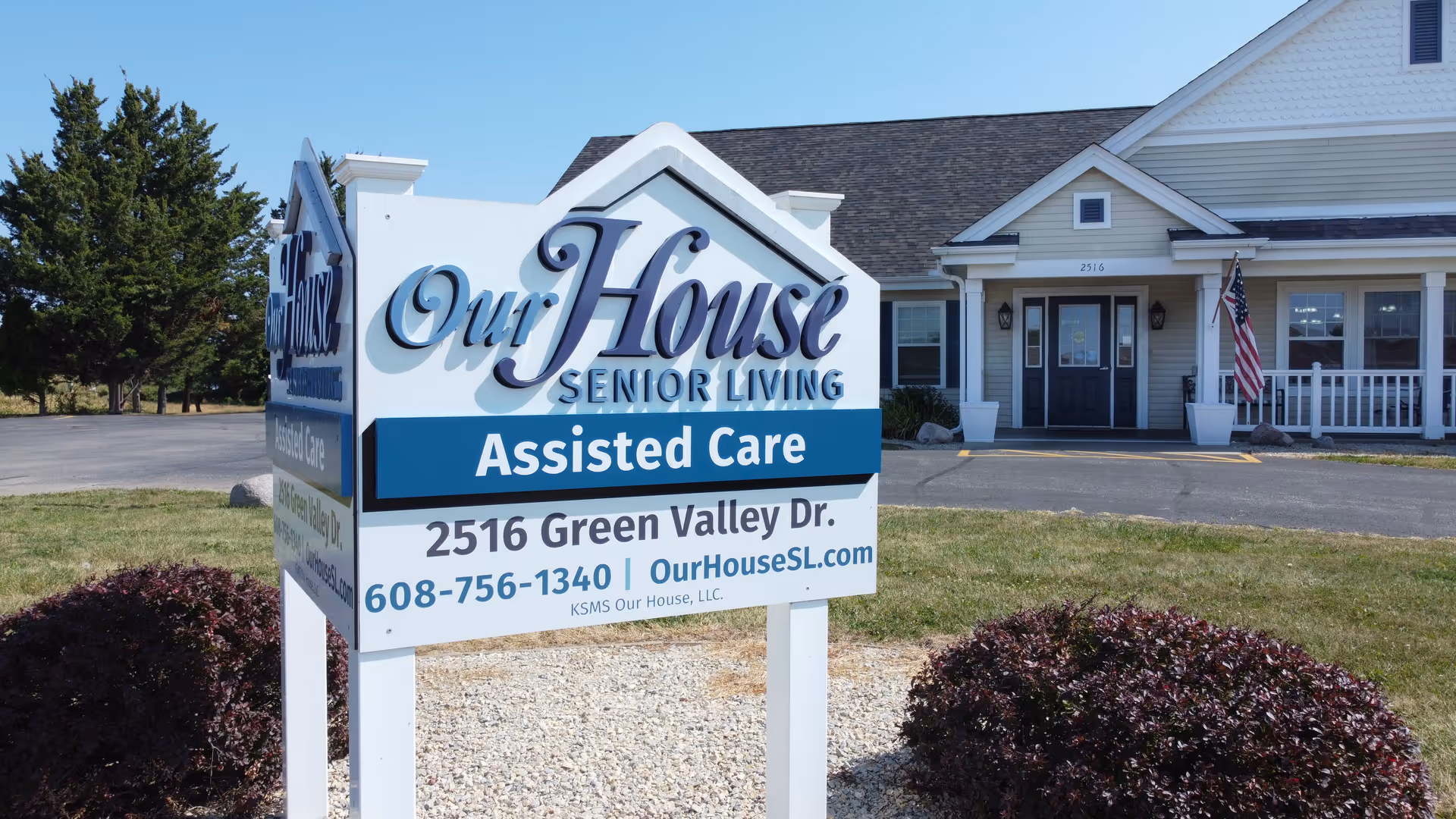 Front sign reading 'Our House Senior Living Assisted Care' with the facility building and entrance visible behind it.