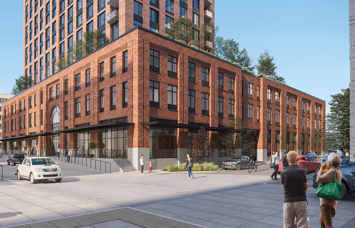 Street-level view of a multi-story red-brick residential building with pedestrians, cars, and trees nearby.