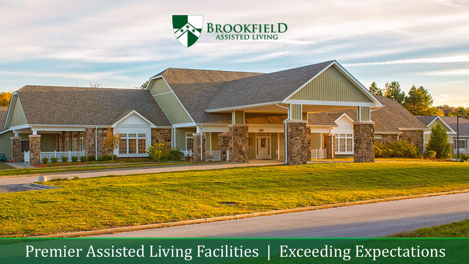 Front exterior of Brookfield Assisted Living with a covered entrance, stone columns, and a landscaped lawn under a clear sky.