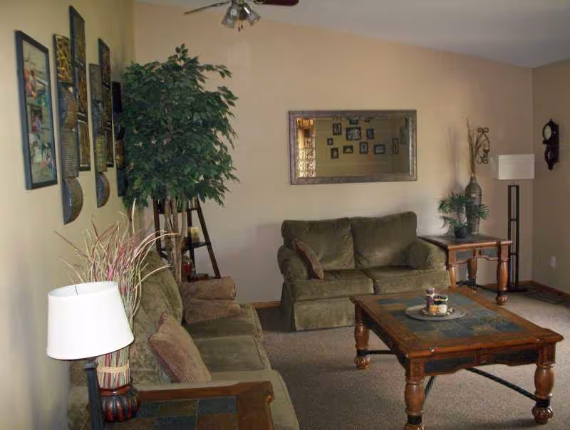 Bradford Home lounge with green sofas, wooden coffee table, plants, and wall art.