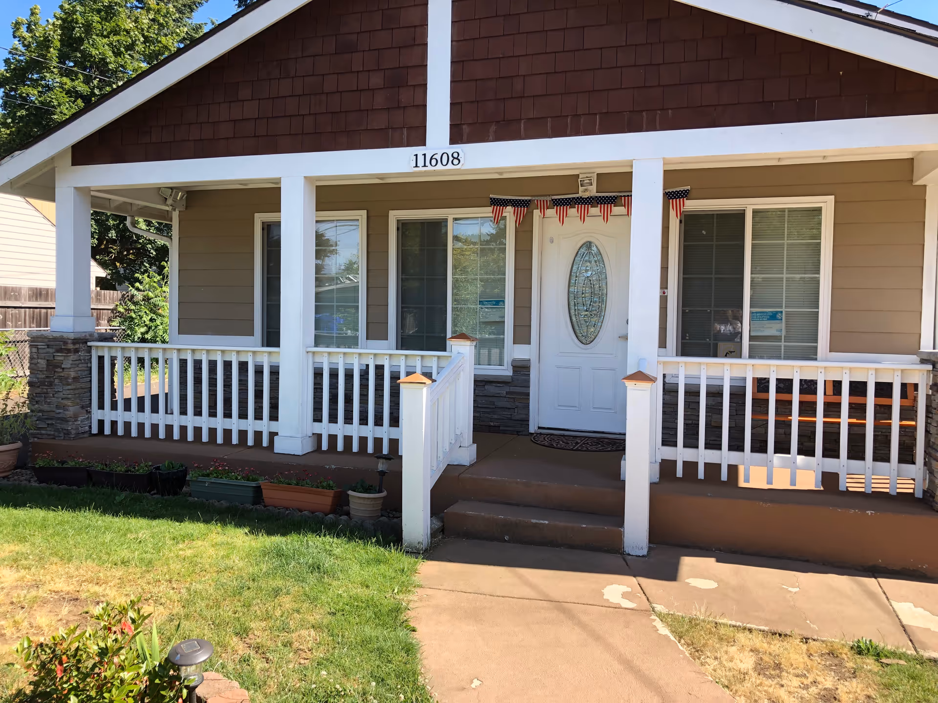 Front porch of a single-story house with white railing, an oval glass front door, and the address number 11608 above the porch.