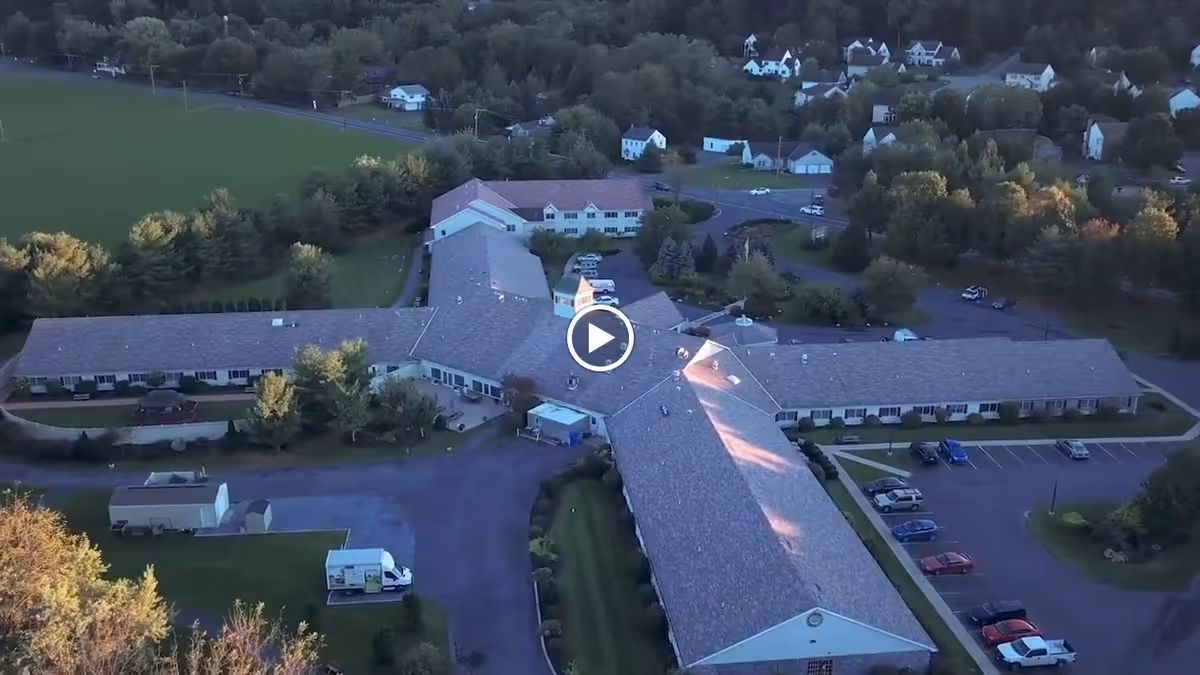 Aerial view of Oak Leaf Manor North, a large senior living facility surrounded by trees and greenery, with parking lots and nearby houses visible.