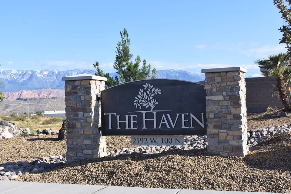 Stone-pillared entrance sign reading "The Haven" with the address and mountains in the background.
