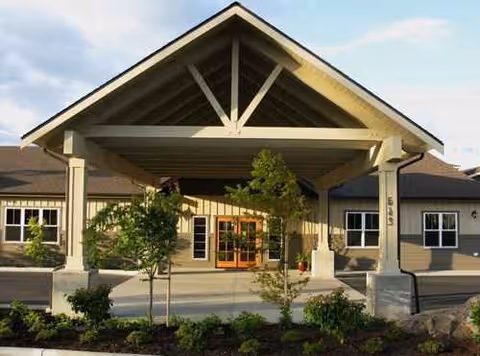 Front entrance of a senior living facility with a covered porch and landscaping.