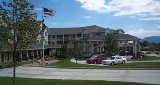 Exterior view of Summit Glen Gracious Retirement Living building with flag and parked cars