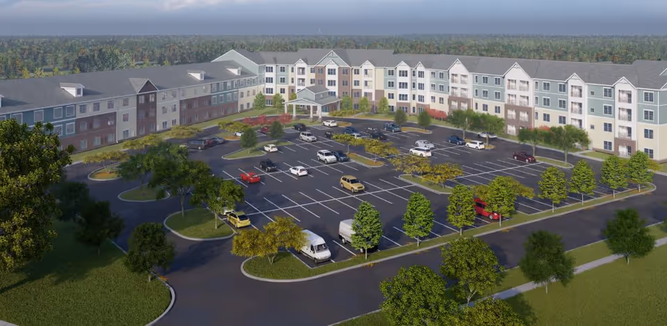 A large multi-story senior living building with a circular parking lot and manicured grounds.